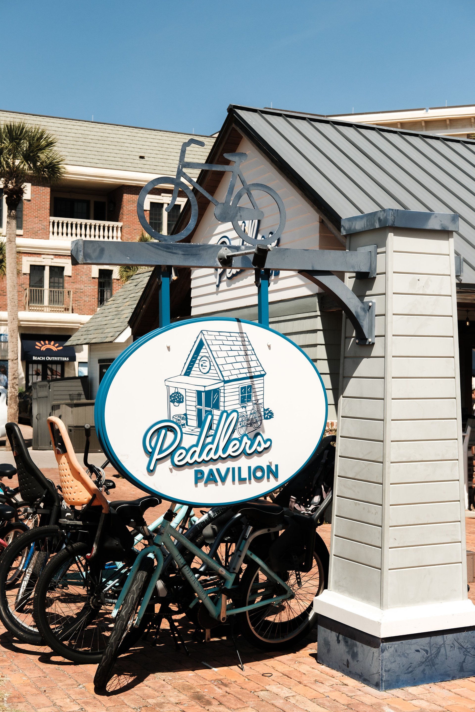 The Peddlers Pavilion sign above a rack of rental bikes